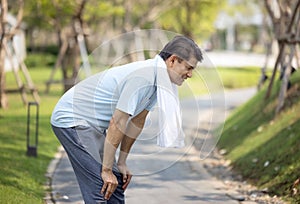 Portrait of sporty healthy mature male in hoodie and running shoes exercising outdoors, practicing side lunges. Elderly bearded