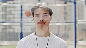 Portrait of sporty male coach standing outdoor on a basketball court turn his head and looking at camera. Concept of