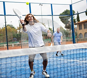 Sporty resolved man playing padel on open court photo