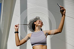 Portrait of sporty smiling young woman after running making selfie outdoors