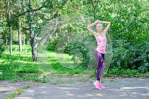 Portrait of sporty woman doing stretching exercises in park before training. Female athlete preparing for jogging