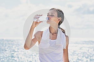 Sporty woman drinking mineral water after workout