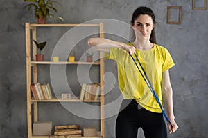 portrait of sporty woman workout with rubber resistance band, performs exercises for the muscles of back and hands