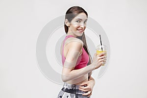 Portrait of sporty young caucasian woman holding plastic glass of orange juice.