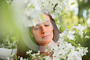 Portrait of spring brunette girl standing outdoor in blooming tr