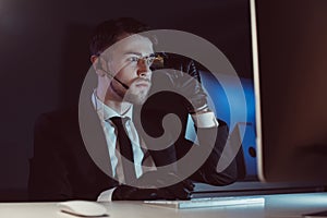 portrait of spy agent with headset looking at computer screen at table