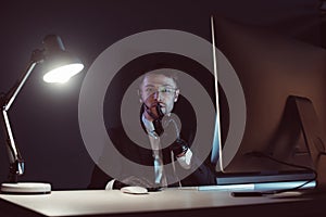 portrait of spy agent showing silence sign at table with computer screen