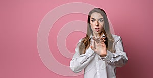 Portrait of startled young brunette woman raising hands and gasping worried, staring shocked and confused at camera