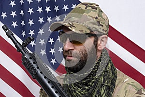 Portrait of a stern military man 30-35 years old with a rifle on his shoulder, wearing dark glasses against the background of the