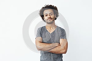 Portrait of stong and handsome african man looking at camera posing with crossed arms over white background. Confident