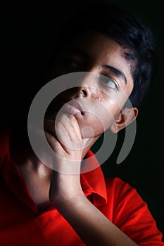 Portrait of a stressed Asian boy in front of black background.