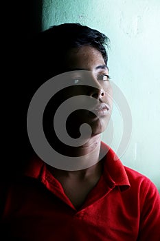 Portrait of a stressed Asian boy in front of black background. An Indian melancholy boy is thinking. Sadness expression of a boy
