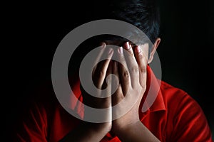 Portrait of a stressed Asian boy in front of black background. An Indian melancholy boy is thinking. Sadness expression of a boy.