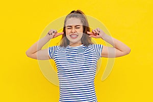 Portrait of stressed brunette young woman plugging ears with fingers and closing eyes tight, irritated with loud annoying noise,