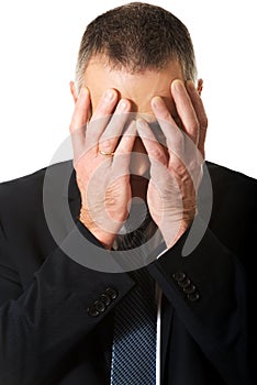 Portrait of stressed businessman covering his face