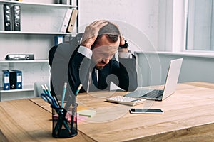 portrait of stressed businessman at workplace with laptop