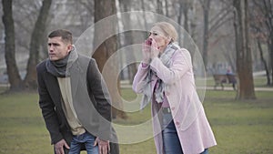 Portrait of stressed Caucasian pet owners losing dog or cat in park. Worried adult man and woman calling and looking