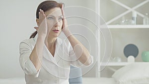Portrait of stressed doctor with headache holding temples with hands and sighing. Tired Caucasian woman having symptoms