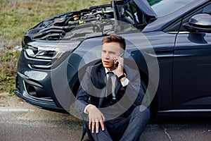 Portrait of stressed young man calling on cellphone for service his breakdown car,