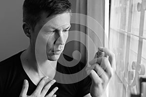 Portrait of stressed young man using asthma inhaler at home