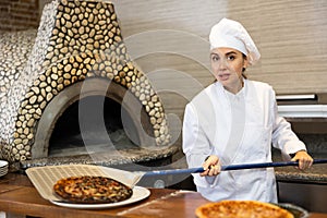 Stressed woman chef preparing pizza in pizzeria