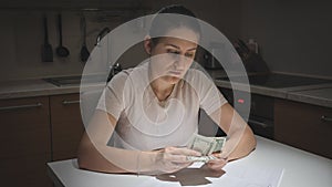 Portrait of stressed young woman having financial problems counting her few money. Concept of financial difficulties