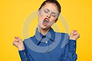 Portrait of a strict woman in a blue shirt with red lips on a yellow background emotions fun