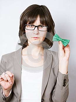 Portrait of a strict woman holding a green bow tie