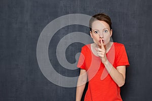 Portrait of strict worried young woman showing shhh taboo sign