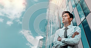 Portrait of a Striving Young Asian Businessman in the City. Crossed Arms and looking up into the Sky photo