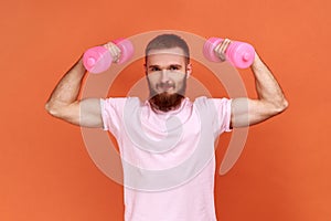 Athletic handsome man holding rose dumbbells in raised arms, healthy lifestyle.