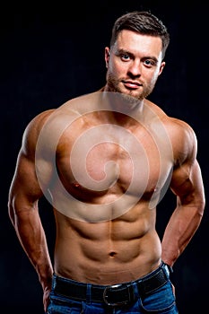 Portrait of strong healthy handsome athletic man fitness model isolated on dark background.