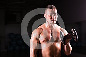 Portrait of strong healthy handsome Athletic Man Fitness Model posing with a dumbbell.