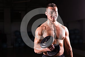 Portrait of strong healthy handsome Athletic Man Fitness Model posing with a dumbbell.