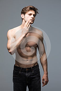 Portrait of strong healthy handsome athletic man fitness model posing gray wall