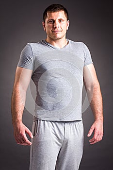 Portrait of strong healthy handsome Athletic Man Fitness Model posing near dark gray wall