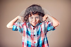 Portrait of a strong kid showing the muscles of his arms