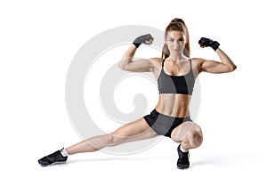 Portrait of strong muscular woman flexing her biceps and stretching leg. Cutout fitness girl.