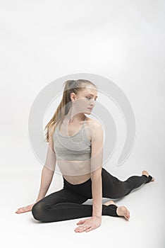 Portrait of strong young fitness woman make yoga stretching exercises on white background. Young girl is doing stretching or