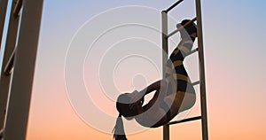 Portrait of strong young woman hanging on wall bars with her legs up. Fitness woman performing hanging leg raises on