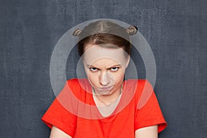 Portrait of stubborn capricious girl looking from under forehead