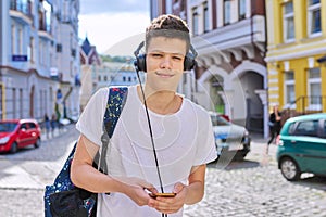 Portrait of student boy teenager with headphones smartphone backpack looking at camera