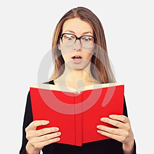 Portrait of student girl in glasses shocked looking in book