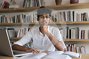 Portrait of student guy posing for camera in university library
