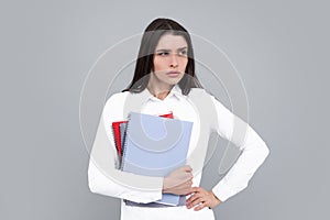 Portrait of student woman. College or high school ducation. Serious woman with notebooks smiling at camera on gray