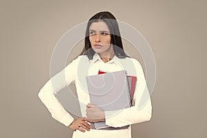 Portrait of student woman. College or high school ducation. Serious woman with notebooks smiling at camera on gray