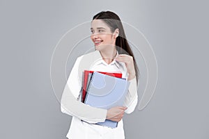 Portrait of student woman. College or high school ducation. Young woman with notebooks smiling at camera on gray studio