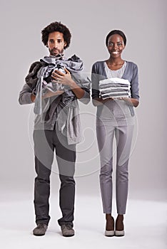 Portrait, studio and people with pile of clothes in hand for laundry day, wash or cleaning together. Woman, smile and