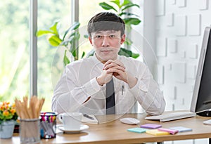 Portrait studio shot of Asian professional successful male businessman employee in formal shirt with necktie sitting look at