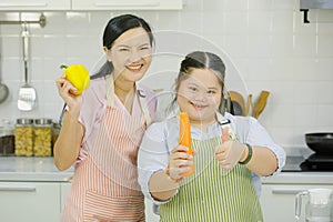 Portrait studio shot Asian young chubby down syndrome autistic daughter holding raw carrot showing thumb up smiling look at camera